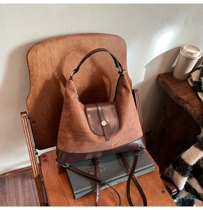 Macro shot of brown suede hobo bag with gold hardware on a wooden chair