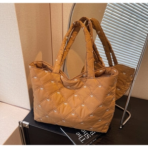 Detail of brown quilted tote bag featuring white bow embroidery and diamond stitching