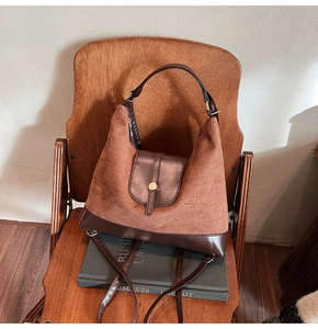 Detailed close-up of brown suede and leather tote bag with a golden metal snap closure