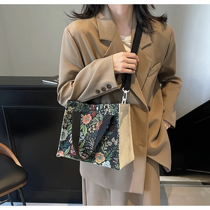 Detail of floral tapestry handbag with beige linen sides and black woven handle