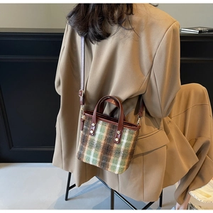 Classic green and brown plaid wool bucket bag with premium leather straps on a model