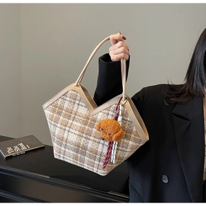 Detail of checkered tote bag with wool texture and cute brown puppy charm