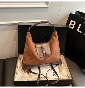 Detail of a brown patchwork hobo bag in a gift box with a golden cylindrical buckle