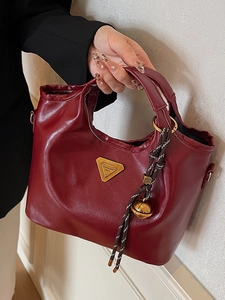 Vintage weinrote glänzende Falten-Handtasche mit Goldbeschlägen und gewebtem Anhänger