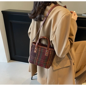 Detail view of retro plaid wool bucket bag with premium leather handles and metal rivets