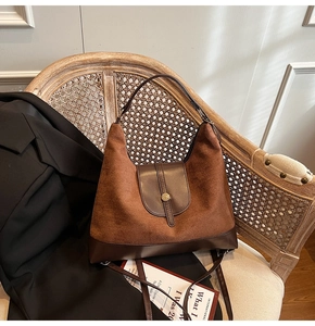 Detail of two-tone tote bag with suede texture, gold buckle, and dual straps on chair