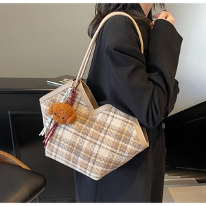 Detailed texture of a vintage plaid tweed tote bag with a brown teddy bear charm