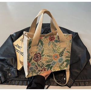 Close-up of floral tapestry tote bag fabric texture with canvas handles and metal snap