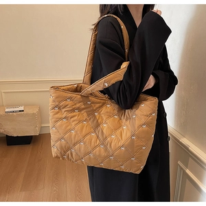 Detail of quilted tote bag with white bow embroidery and spacious shoulder strap