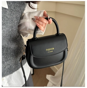 Detail of black faux leather saddle bag with yellow printed logo and metal hardware