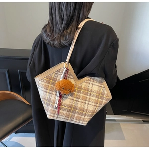 Detail of checkered tote bag with V-shaped cut and cute brown teddy dog pendant