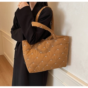 Detail view of brown quilted tote bag with white bow pattern and soft nylon fabric texture