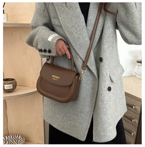 Brown matte leather saddle bag shown with a grey herringbone blazer on a model