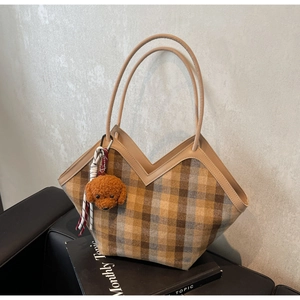 Detail of vintage plaid handbag featuring V-shaped cut and plush dog charm on side