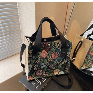 Close-up of floral embroidery on linen crossbody bag with adjustable strap and handles