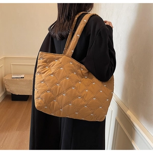 Close-up of brown quilted tote bag with white bows and glossy nylon texture