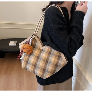 Close-up of large plaid tote bag featuring leather handles and brown teddy bear charm