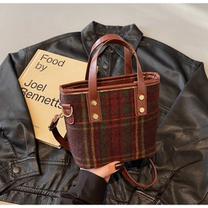 Detail of red and green plaid woolen tote with brown leather strap and gold hardware