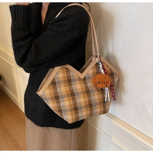 Detail of a brown plaid tote bag with V-shaped opening and cute teddy bear charm