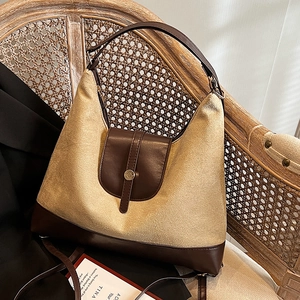 Large beige retro hobo tote bag with brown leather trim on a rattan chair