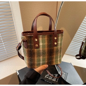 Macro detail of plaid wool fabric and brown leather handle with golden metal rivets