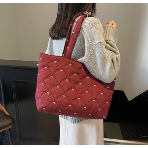 Close-up of wine red quilted tote bag with white bows and diamond stitching
