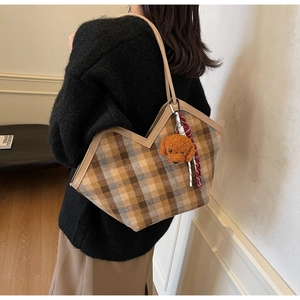 Detail view of large brown plaid shoulder bag with a V-cut edge and cute teddy bear pendant