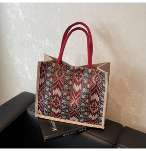 Detail of bohemian geometric pattern tote with red circular handle on leather sofa