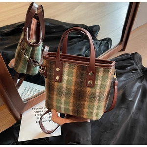 Detail view of vintage wool plaid bucket bag with leather handles and gold-tone metal hardware
