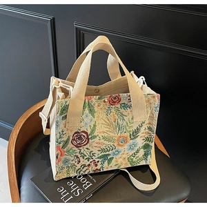 Detail of floral tapestry handbag featuring wide cotton straps on a vintage wooden chair