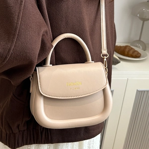Creamy beige fashion saddle bag with gold metal hardware and adjustable shoulder strap
