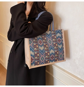 Detail of bohemian geometric woven tote bag featuring blue handles and ethnic pattern