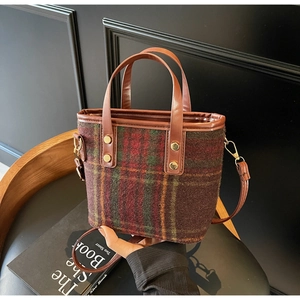 Detail view of multicolored plaid wool handbag with leather straps and gold hardware