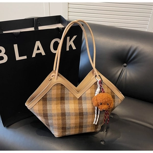 Detail shot of a plaid tote bag with V-shaped opening and cute brown teddy charm