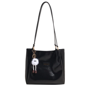 Glossy black patent leather tote bag with fashionable shoulder straps and plush charm