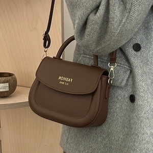 Brown matte leather saddle bag with gold metal hardware and adjustable shoulder strap