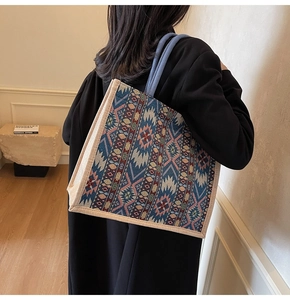 Detail of large woven linen tote bag featuring geometric patterns and blue rope handles