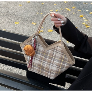 Detail of checkered tweed tote bag featuring V-cut edge and a cute brown plush bear charm