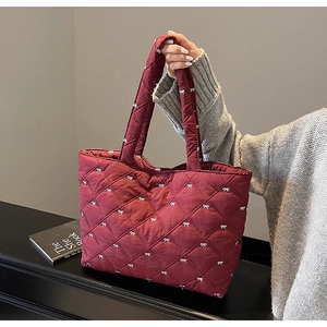 Close-up of quilted burgundy tote bag with white bow embroidery and diamond stitching