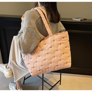 Detailed view of pink quilted tote bag with embroidered bows and soft padded straps