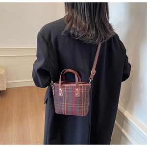 Detailed back view of a plaid woolen bucket bag with leather straps and gold rivets