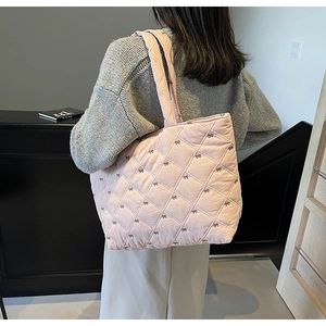 Detail of pink quilted tote bag with bow embroidery and rhombus pattern for women