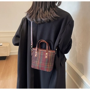 Fashionable red and green plaid woolen bucket bag worn on a model in a black blazer