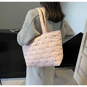 Detail of pink quilted tote bag with bow accents and casual shoulder strap design