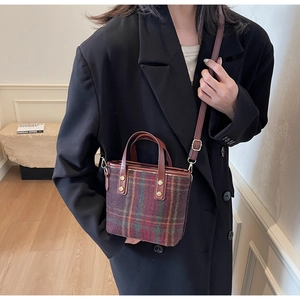 Detailed view of plaid wool bucket bag with leather handles and gold-tone hardware accents