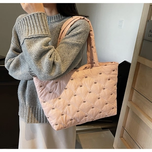 Detail of pink quilted tote bag featuring delicate black bow embroidery and soft texture