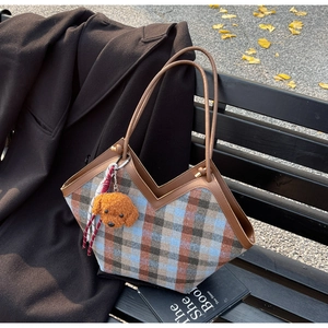 Large capacity plaid tote bag with brown leather handles on a park bench