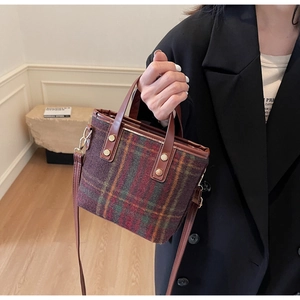 Detail of plaid wool tote bag with leather straps and decorative gold metal rivets