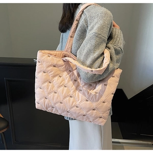 Detailed side view of pink quilted tote bag with bow embroidery worn by a model