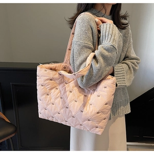 Pink quilted tote bag with bow embroidery detail and dual handles for shoulder carry